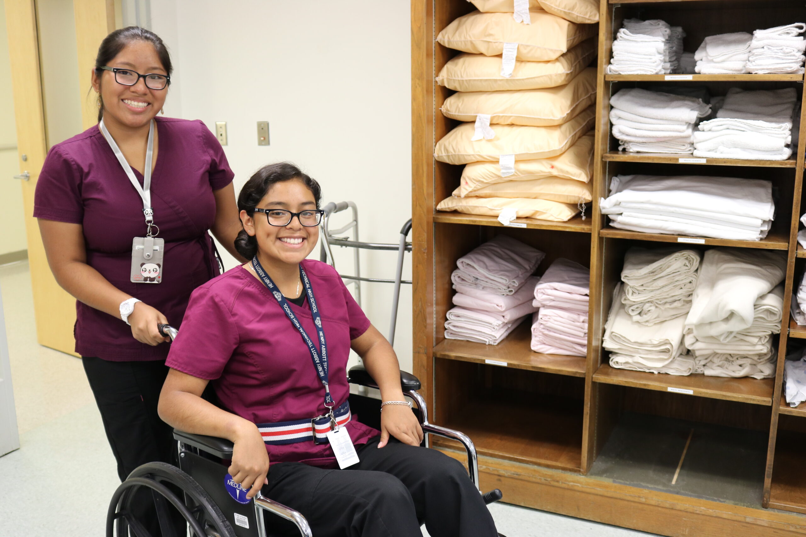Two health tech students, one in wheelchair and the other standing behind wheelchair
